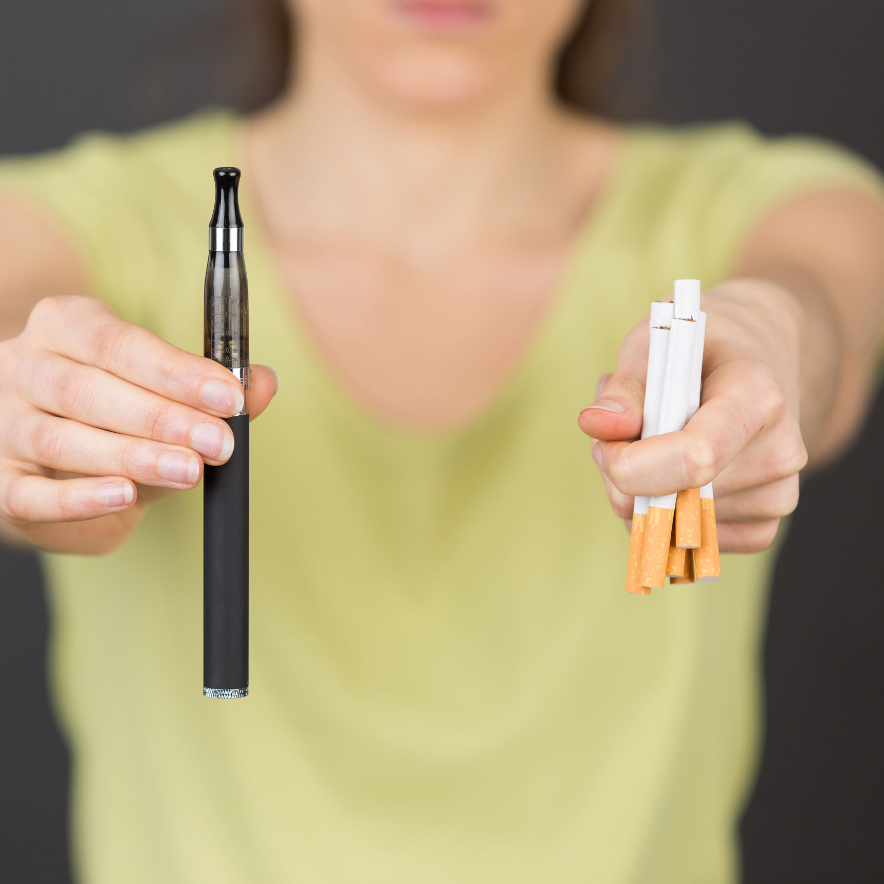 Foto af person der holder cigaretter og e-cigaret i hænderne