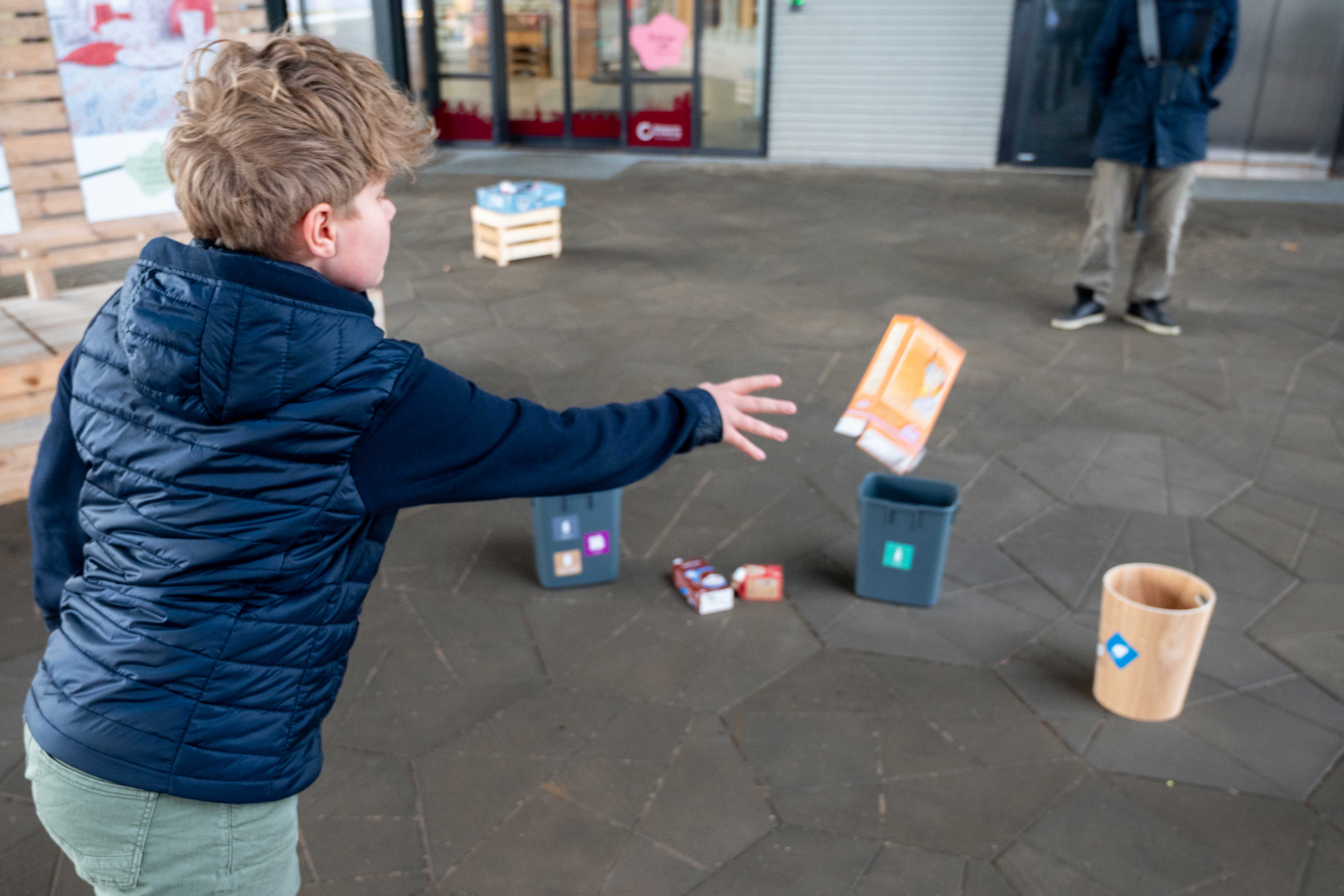 Barn kaster med papcontainer som en del af aktiviteten "affaldsbingo" på Torvet ved RessourceCenter Vejle i forbindelsen med fejringen af RCV's 2-års fødselsdag-