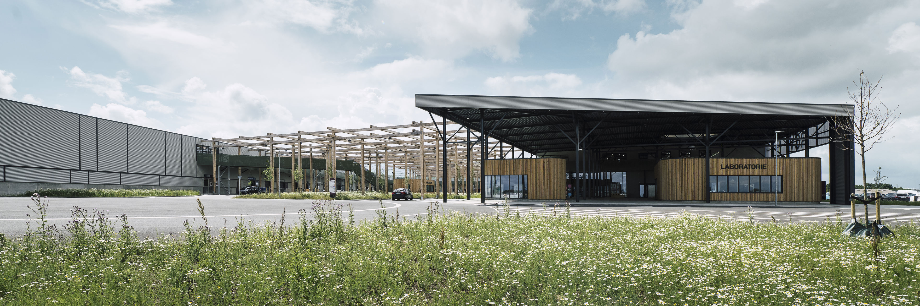 RessourceCenter Vejle (RCV) med grønt tag og solpaneler, omgivet af grønne områder, der viser centerets bæredygtige arkitektur og indre gårdstruktur.