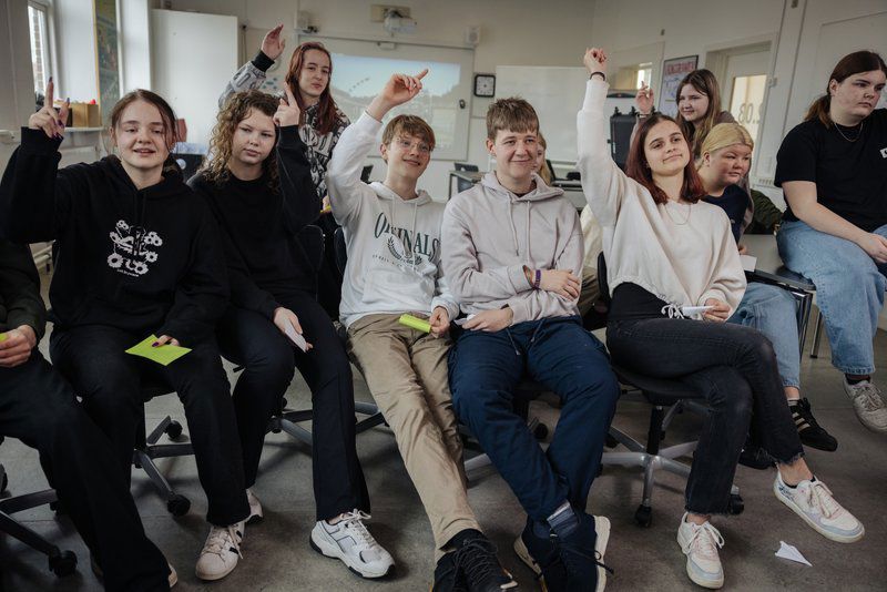 Unge der rækker hånden op i klasseværelse