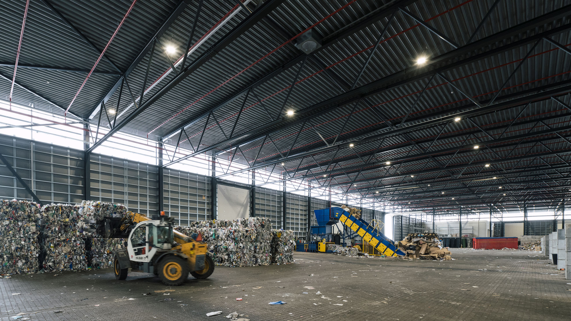 Indvendig hal med affaldshåndtering på RessourceCenter Vejle. Stor industrihal med maskiner og affald i forskellige fraktioner.