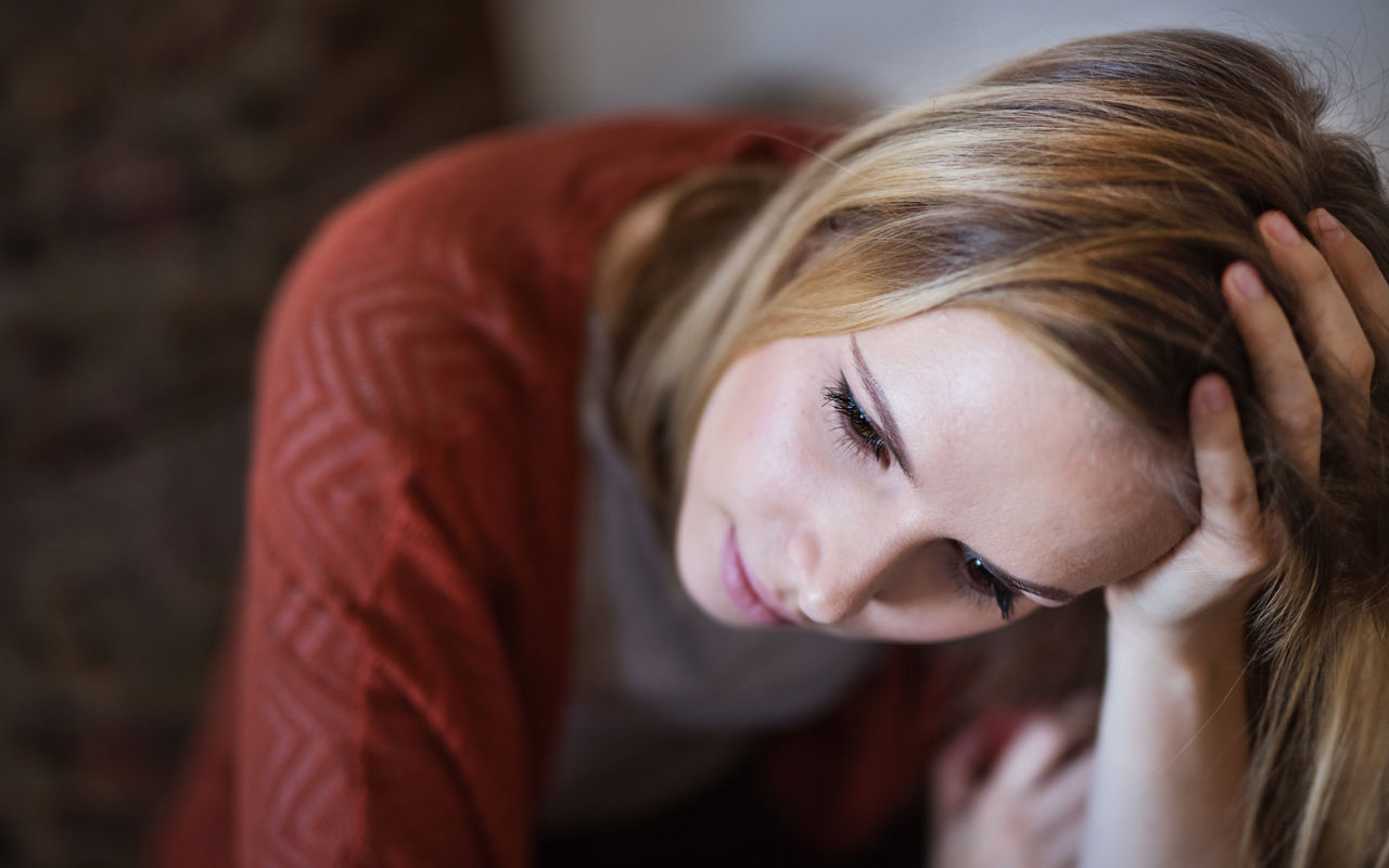 Portræt af ung kvinde der hviler sit hoved i den ene hånd