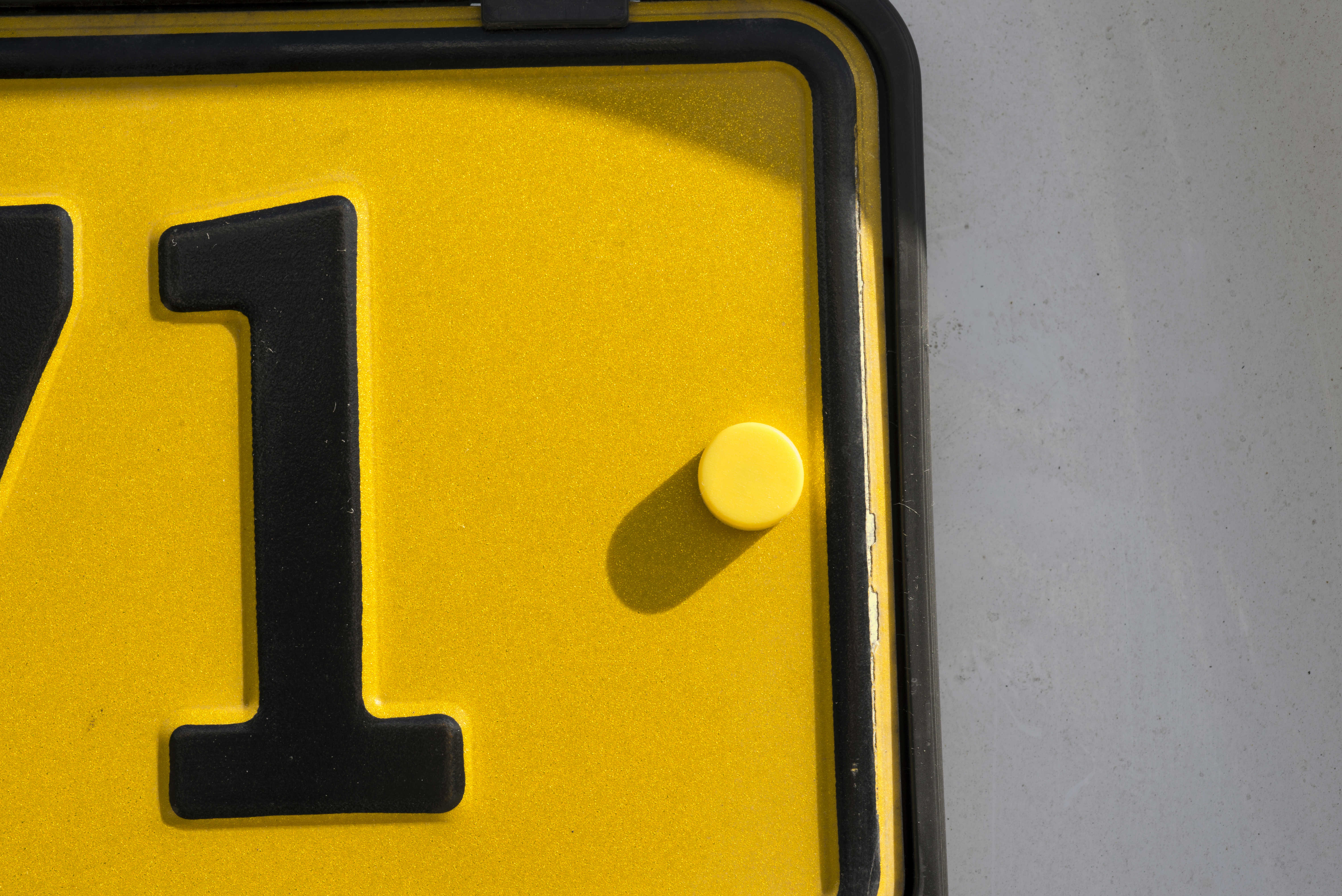 Et hjørne af en gul nummerplade med tallet 1.